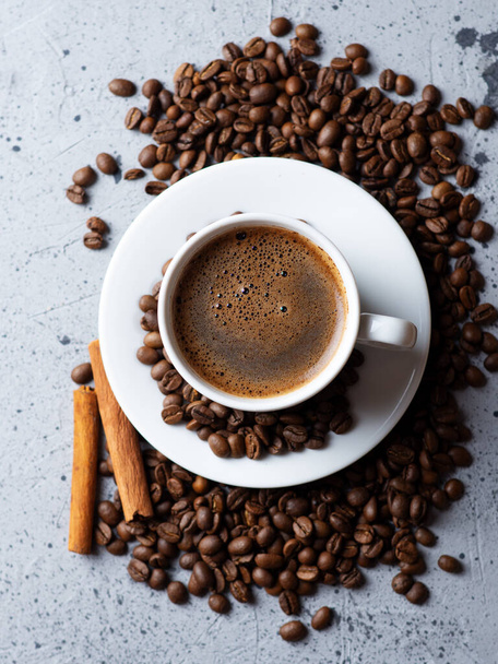 Zbliżenie filiżanki kawy z białym espresso, rozrzucone palone ziarna kawy i cynamon - Zdjęcie, obraz