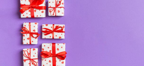Composición festiva de cajas de regalo con corazones rojos sobre fondo colorido con espacio vacío para su diseño. Vista superior del concepto de San Valentín. - Foto, Imagen