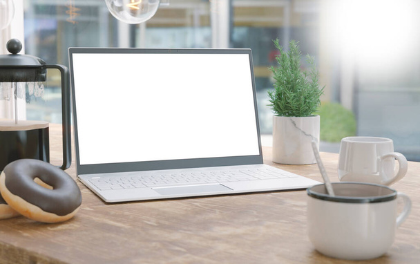 Generischer Laptop und Kaffeetasse auf einem Holztisch. Leerer Bildschirm für Attrappen - Foto, Bild