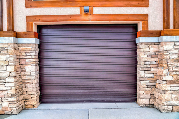 Porte de garage entre piliers en brique de pierre avec allée pavée au premier plan - Photo, image