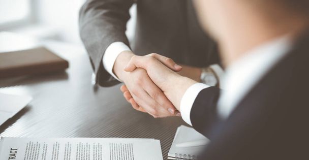 Unknown businessman shaking hands with his colleague or partner above the glass desk in modern office, close-up. Business people group at meeting - Foto, Imagen