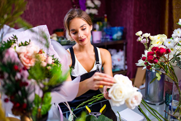 young woman flower store manager standing at workplace and smiling reopening shop sale - Fotoğraf, Görsel