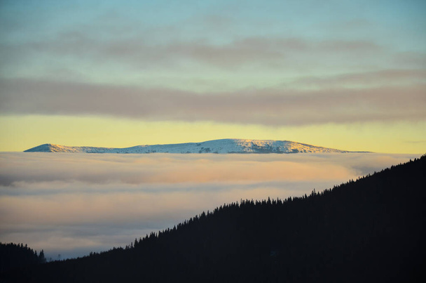 Gün batımında bulutlarla kaplı bir dağ sırası. Karpatlar. - Fotoğraf, Görsel