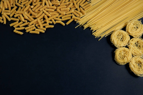Assortment of different types of pasta dry on black background. - Foto, immagini