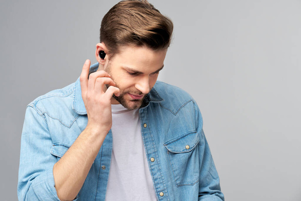 Close up portrait of cheerful young man enjoying listening to music wearing casual jeans outfit - Foto, imagen