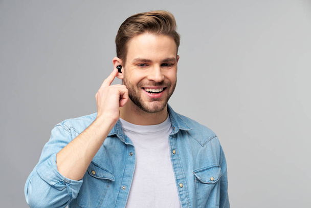 Close up portrait of cheerful young man enjoying listening to music wearing casual jeans outfit - Photo, image
