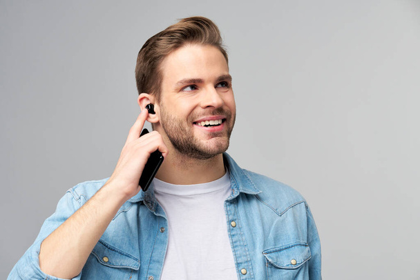 Close up portrait of cheerful young man enjoying listening to music wearing casual jeans outfit - Photo, Image