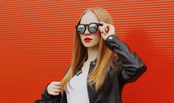 Portrait of young blonde woman in sunglasses on a red background - Foto, immagini