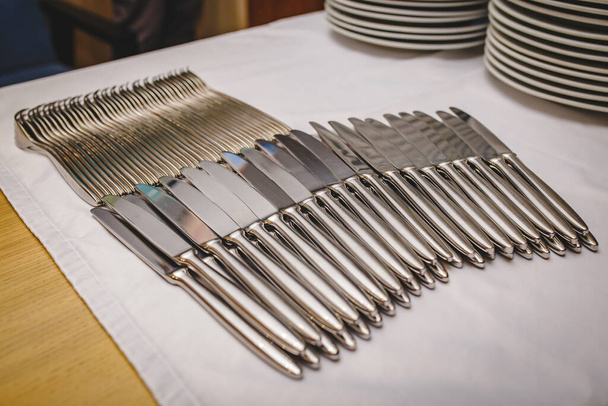 wiele czystych noży stalowych leży w rzędzie na obrusach w restauracji z talerzami na tle - Zdjęcie, obraz