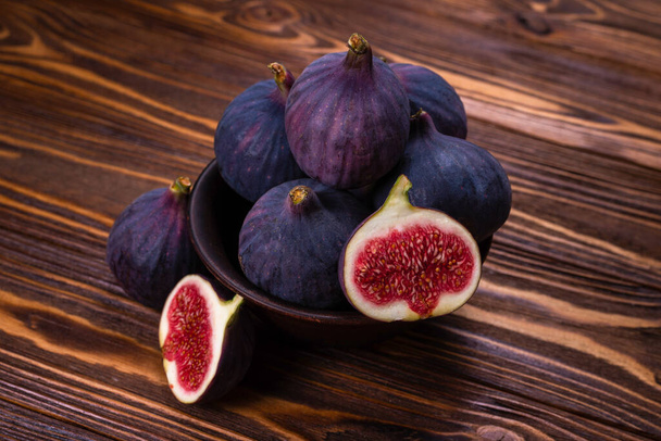 Tasty figs in a bowl on wooden background. Top view. Slices.   - Foto, immagini