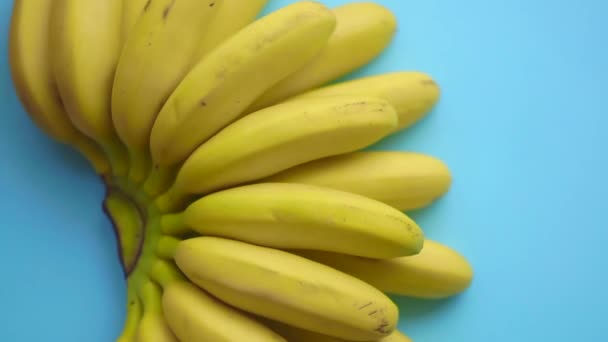 Il ramo delle banane ruota su uno sfondo colorato. Cibo video d'arte minimale. Concetto di vitamine estive vegetariane - Filmati, video