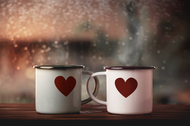 Concepto de Amor y San Valentín. Pareja de taza de café con forma de corazón por ventana de vidrio en la casa. Felicidad, Mente Romántica o Positiva en el Día Lluvioso - Foto, imagen