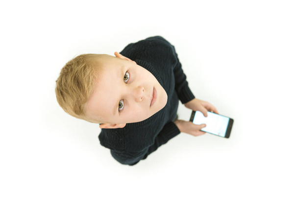 The serious boy stand with a smartphone. View from above - Фото, изображение