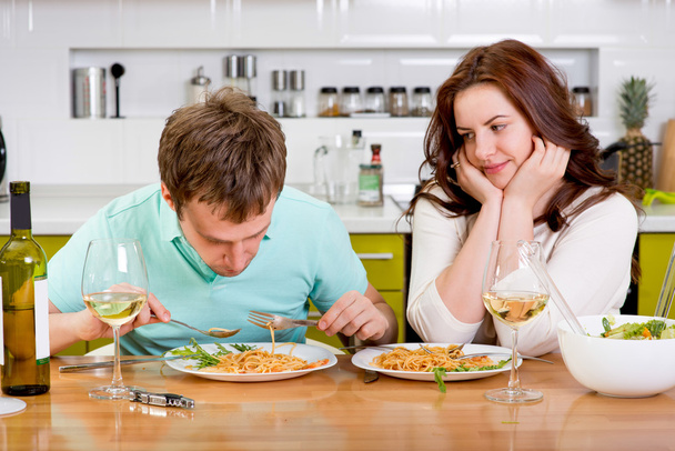 żona entuzjastycznie patrząc, podczas gdy jej mąż jeść makaron na - Zdjęcie, obraz