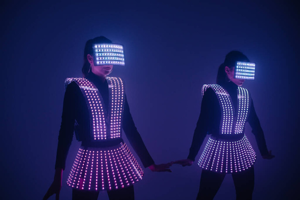 Zwei sexy Disco-Tänzerinnen bewegen sich in UV-Kostümen. Feste und Tänze. - Foto, Bild