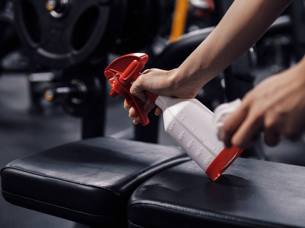 Staff disinfecting a gym equipment using sanitizer - Foto, imagen