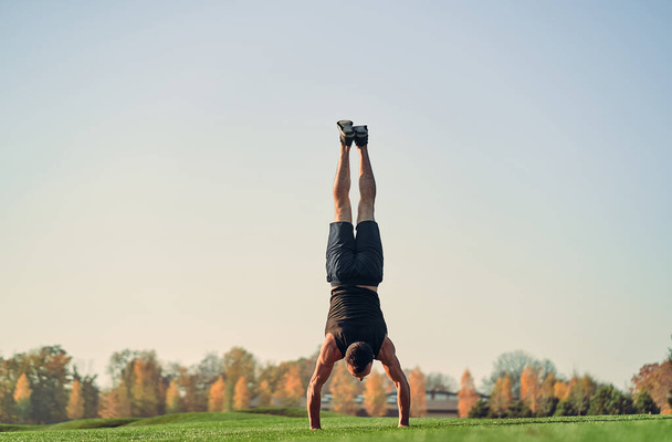 Sportovec stojící na rukou na trávě - Fotografie, Obrázek