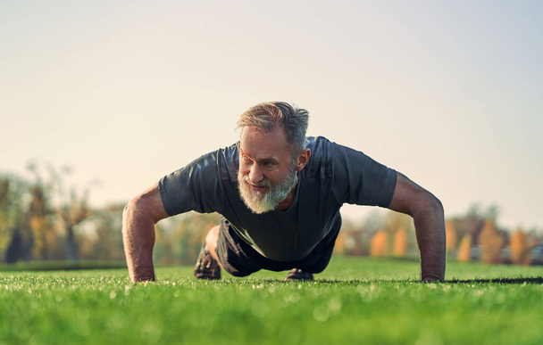 El viejo deportista empujando sobre la hierba - Foto, Imagen