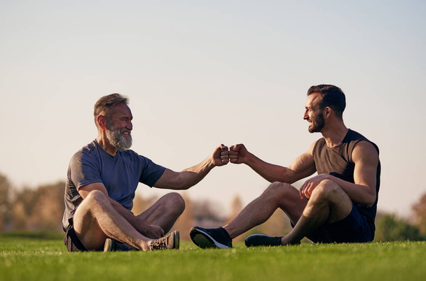 Ti dva muži seděli na trávě a zdravili - Fotografie, Obrázek