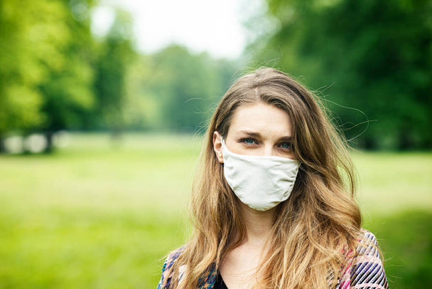 A young woman in a face mask in a nature, park during the spring - Φωτογραφία, εικόνα