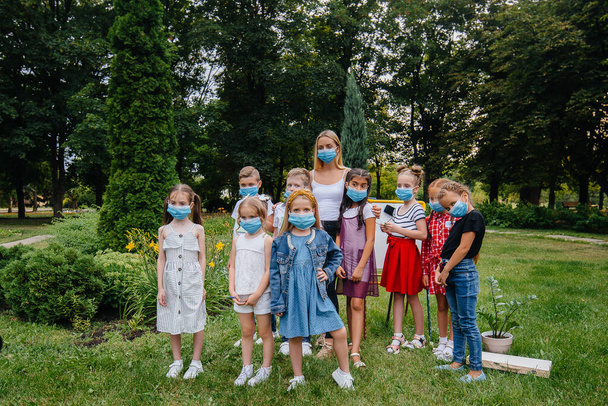 A class of masked school children is engaged in outdoor training during the epidemic. Back to school, learning during the pandemic - Fotografie, Obrázek