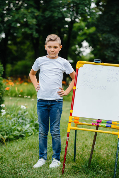 The student writes lessons on the blackboard and is engaged in outdoor training. Back to school, learning during the pandemic - Fotografie, Obrázek