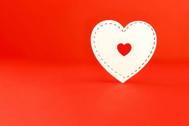 Corazón blanco sobre fondo rojo. Concepto de amor. Día de San Valentín, gracias, caridad. Prepárate para tu mensaje. Tarjeta de felicitación o invitación - Foto, imagen