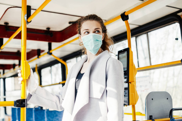 A woman wearing surgical protective mask in a public transportation - Foto, Bild