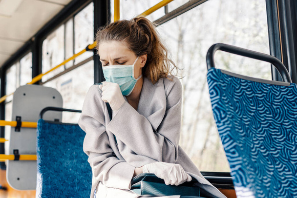 Una joven en el transporte público con máscara facial. La mujer está tosiendo y ahogándose. - Foto, imagen