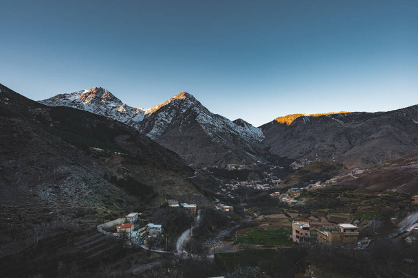 Mountains surrounding a small berber village in Morocco during sunrise sunset. Snow capped mountain panorama. Blue sky during summer hike. - Fotó, kép