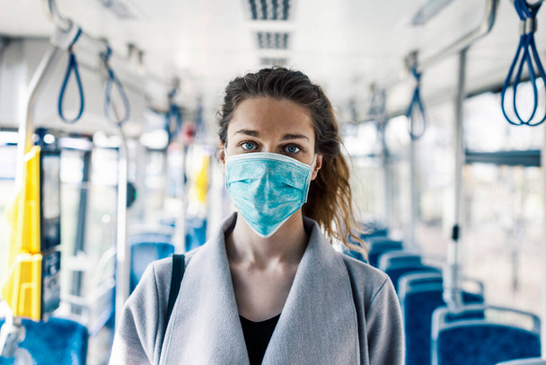 A young woman in the public transportation wearing face mask and gloves. - Fotografie, Obrázek