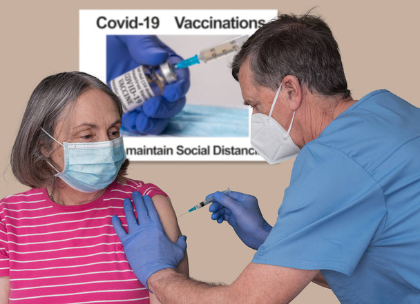 Senior male doctor vaccinating a retired woman in clinic for coronavirus - Photo, Image
