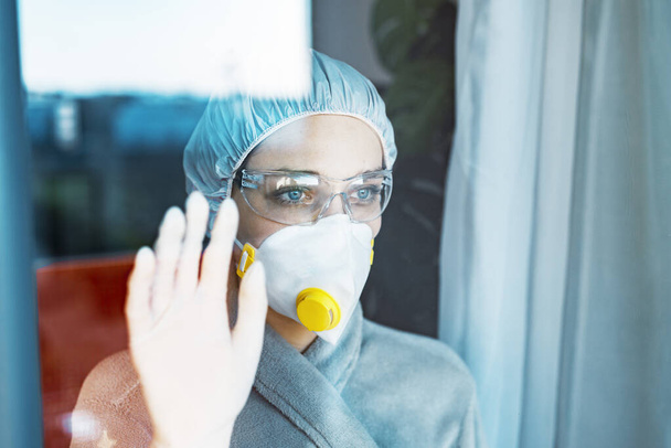 Карантин під час спалаху вірусу вдома або в лікарні, жінка дивиться через вікно
 - Фото, зображення