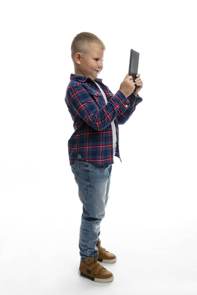 Fat boy schoolboy looks at the tablet. Full height. White background. Distance learning. Vertical. - Fotó, kép