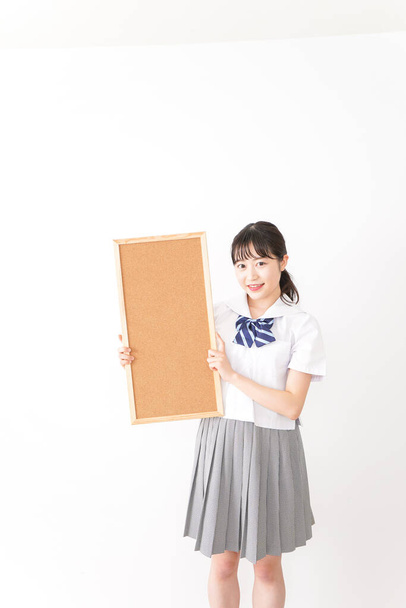 mladá asijská studentka v uniformě držení deska - Fotografie, Obrázek