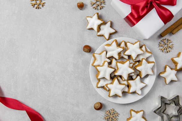 Christmas traditional German cookies, cinnamon stars with hazelnuts, decoration and tree branches on a light concrete background. Top view. Copy space. - Photo, image