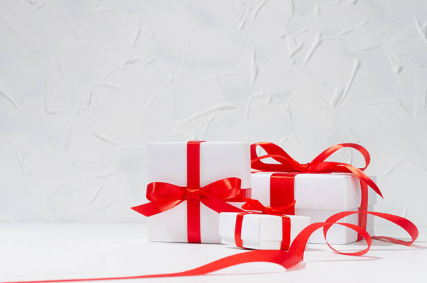 White different size gift boxes with red silk ribbon in white interior, copy space, wedding background. - Fotoğraf, Görsel