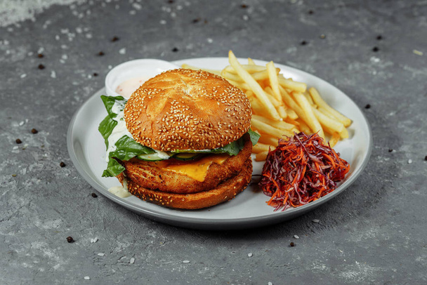 chicken burger with french fries and salad on an old concrete background. - Zdjęcie, obraz