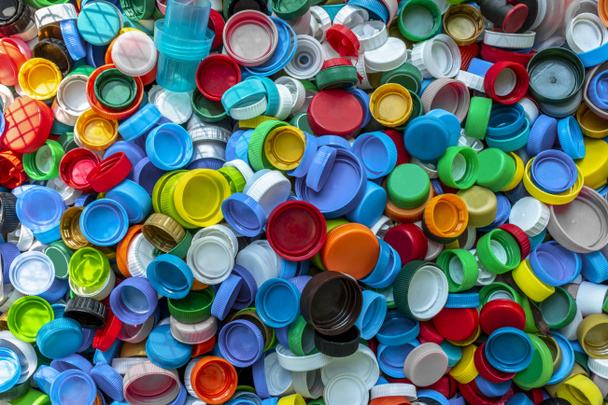 De nombreux bouchons de bouteilles en plastique multicolores à usage unique sont collectés pour le recyclage. Recycler le plastique, l'écologie, la gestion des déchets, le concept des questions environnementales. Contexte. Collecte des déchets plastiques - Photo, image