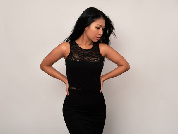 Beautiful asian woman with long black hair posing in dress on grey background - Photo, Image