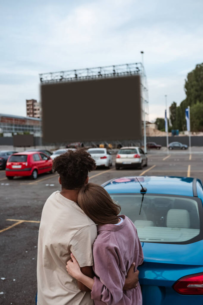Young pair watching movie while hugging at autocinema - Valokuva, kuva