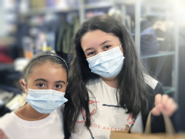 Zwei junge Mädchen beim Einkaufen mit Gesundheitsmasken in Covid Prävention. - Foto, Bild