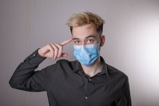 portrait of an outraged teenager in a medical mask on a contrasting background. Concept: anger of young people, questioning facial expressions, emotions during the pandemic. - Fotoğraf, Görsel