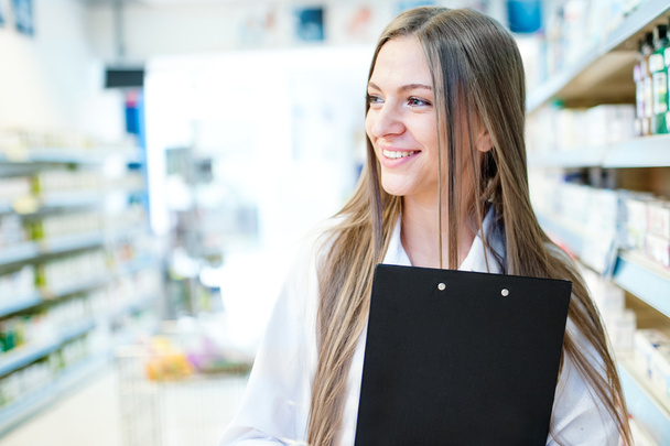 Portrait of smiling blonde female pharmacist with a beautiful smile standing in pharmacy - Foto, imagen