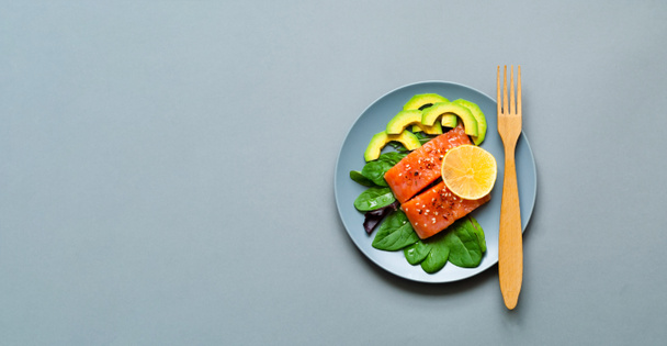 Salmon fillets with spinach and avocado in blue plate on gray background. Concept health-conscious. Close-up, copy space. Top view. - 写真・画像