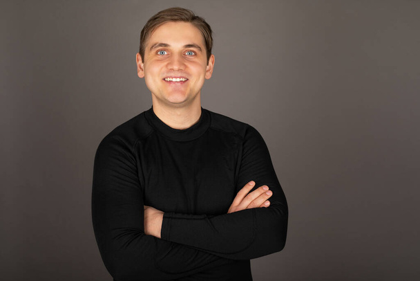 Portrait of a caucasian handsome man wearing black blouse, posing in front of grey background - Фото, зображення