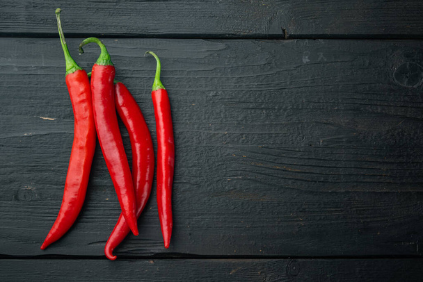 Ripe red chili peppers set, on black wooden background, top view or flat lay with copy space for text - Foto, imagen