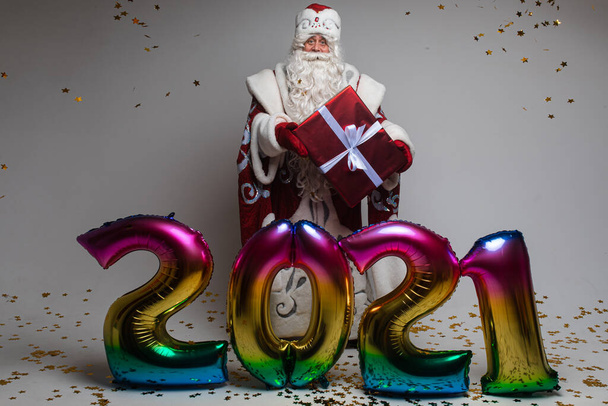 Palloncini colorati a forma di 2021 e Babbo Natale con regalo che celebra Natale e Capodanno - Foto, immagini