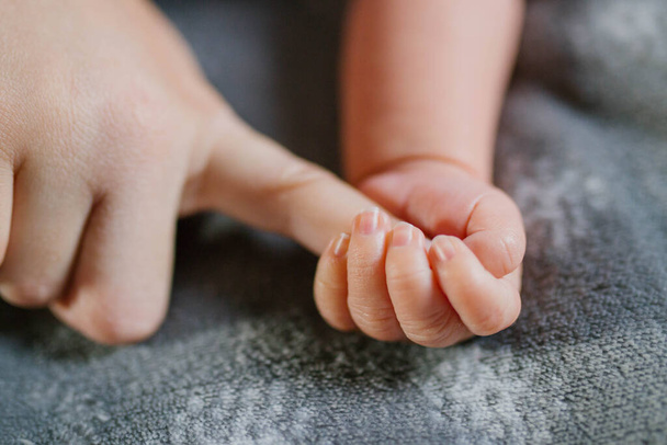 Küçük bir bebeğin eli annenin parmağını tutuyor. - Fotoğraf, Görsel