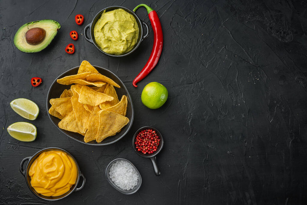 Mexikanische Nachos-Chips mit Dip-Sauce, auf schwarzem Hintergrund, von oben oder flach mit Textspeicher - Foto, Bild